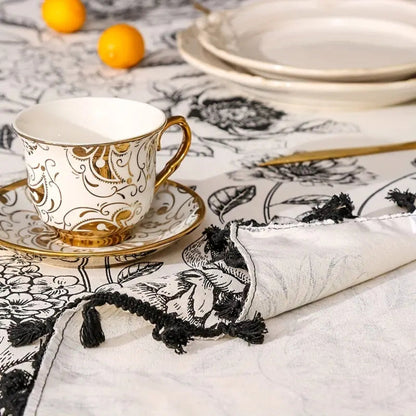 Detail view of black floral tasseled farmhouse tablecloth with intricate floral patterns and a rustic touch.